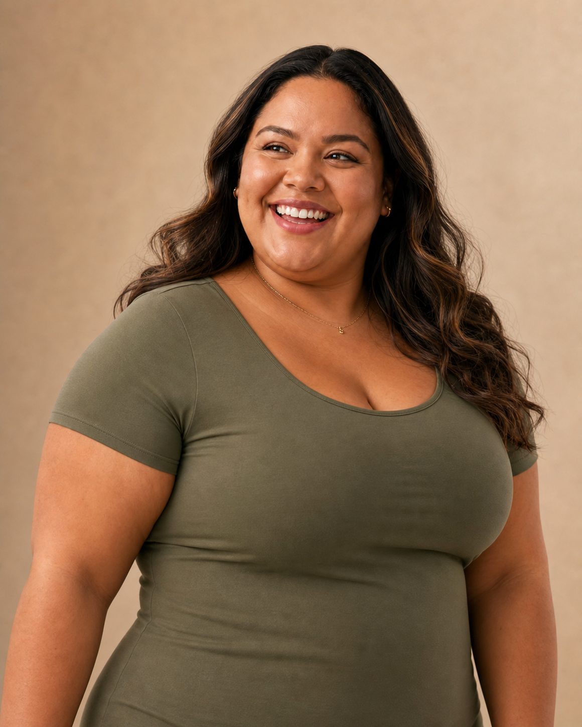 A smiling woman in an olive top against a warm neutral backdrop